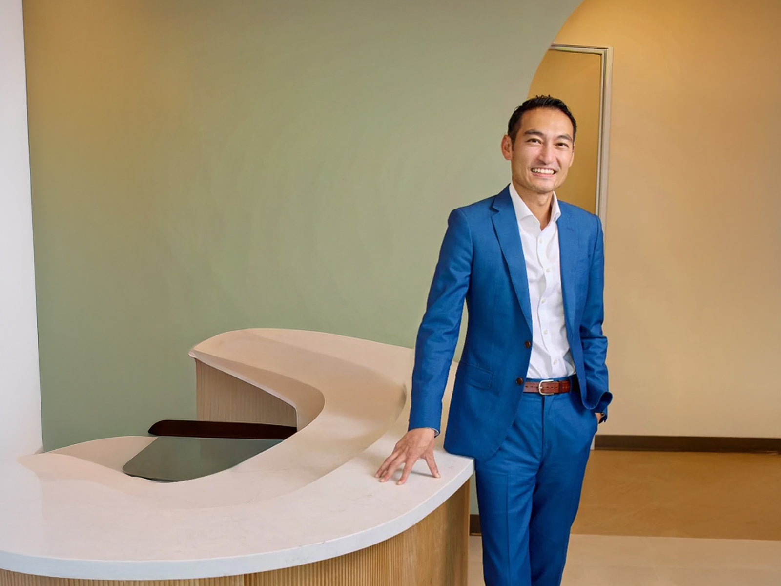 Dr. Charlie Chen in a blue suit at the sage reception desk of his San Diego practice